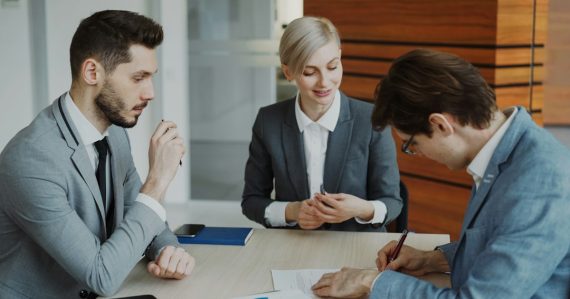 Business people signing a contract at a table, illustrating cloud computing for law firms