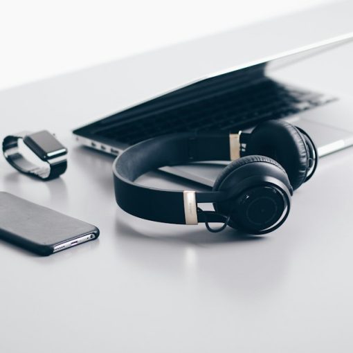 Black cordless headphones beside closed black laptop computer, illustrating desktop virtualization for consumer devices