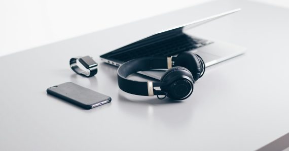 Black cordless headphones beside closed black laptop computer, illustrating desktop virtualization for consumer devices