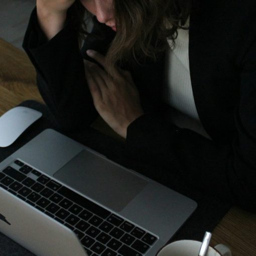 Stressed woman with head in hands at laptop, illustrating the coming crisis of IT management