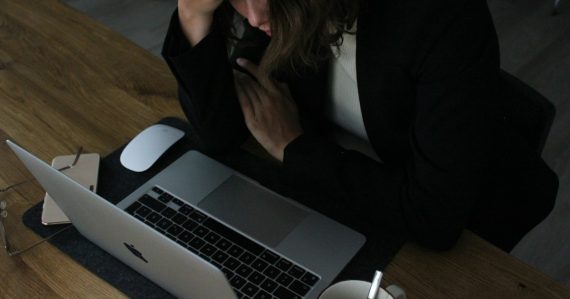 Stressed woman with head in hands at laptop, illustrating the coming crisis of IT management