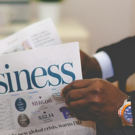 Person wearing suit reading business newspaper, illustrating mid-sized firms investing in the cloud