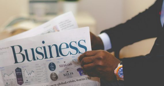 Person wearing suit reading business newspaper, illustrating mid-sized firms investing in the cloud