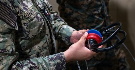 Two people in military uniforms holding headphones, illustrating military use of cloud computing