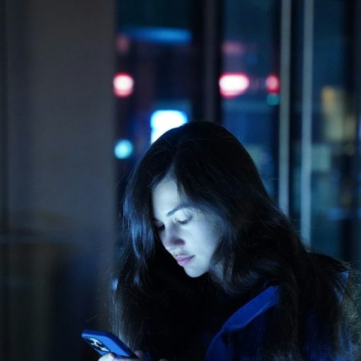 A woman in a blue jacket looking at her cell phone, illustrating mobile cloud computing market growth