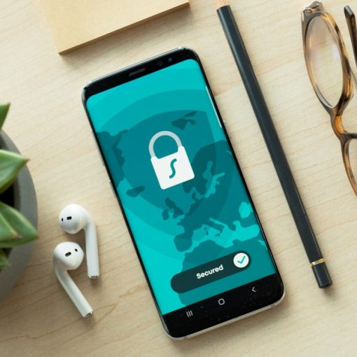 A smartphone displaying a security lock icon on a wooden desk, illustrating cloud computing in mobile security