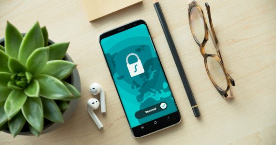 A smartphone displaying a security lock icon on a wooden desk, illustrating cloud computing in mobile security