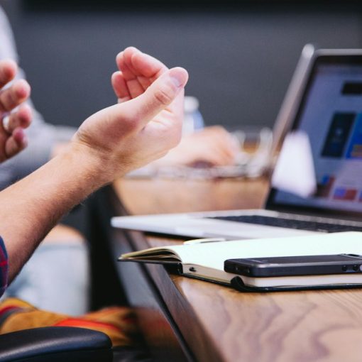 Person gesturing during meeting with laptop, illustrating motivations behind the move to cloud computing