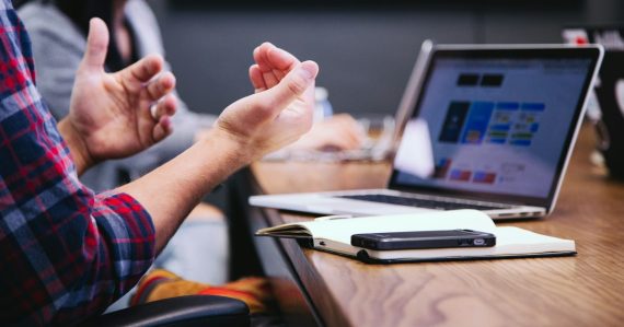 Person gesturing during meeting with laptop, illustrating motivations behind the move to cloud computing