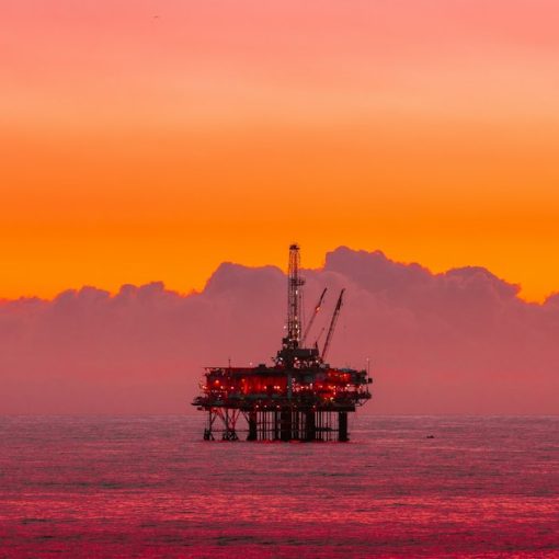An oil rig in the middle of the ocean at sunset, illustrating cloud-ready networks for oil and gas