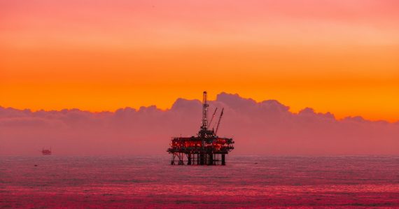 An oil rig in the middle of the ocean at sunset, illustrating cloud-ready networks for oil and gas