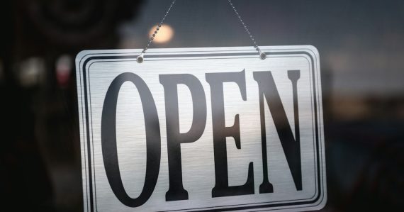An open sign hanging on a glass door, illustrating the open cloud