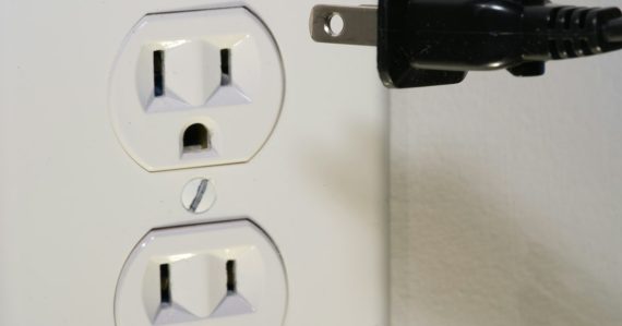 Black plug in front of electric socket, illustrating the need for open cloud standards