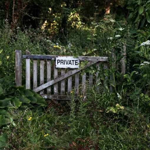 A weathered wooden gate with a PRIVATE sign in a dense garden, illustrating challenges in building private clouds
