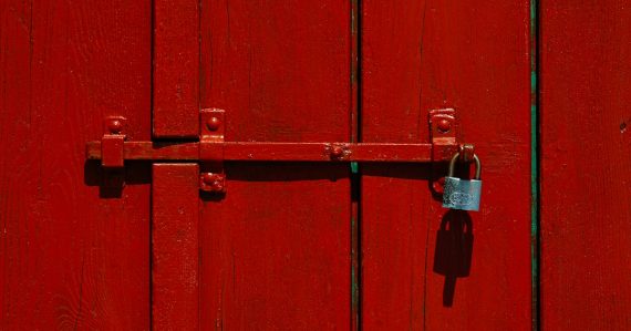 Red wooden door with a locked padlock, illustrating private versus public cloud security