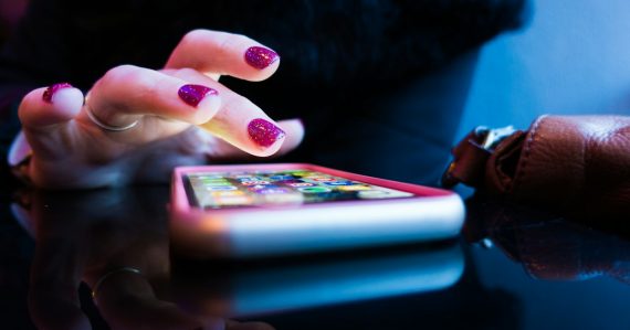 Person using black smartphone with gray and pink case, illustrating public cloud for mobile apps