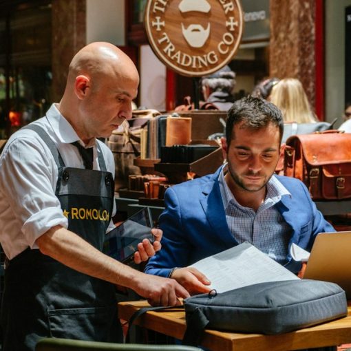 Two men looking at laptop and papers in store, illustrating deciding if SaaS fits a small business