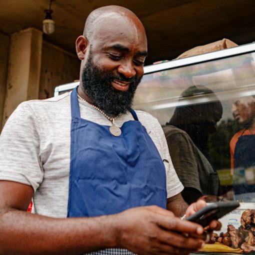 A shop owner in an apron looking at a cell phone, illustrating SaaS for small and mid-sized businesses