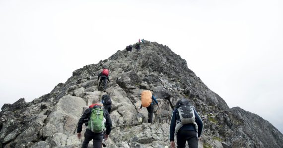 Climbers hiking toward a mountain peak, illustrating scaling the cloud for high-tech companies