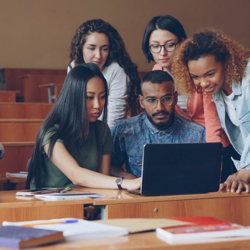 Group of students gathered around a laptop, illustrating schools turning to cloud computing