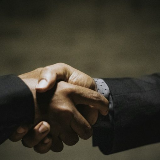 Two people shaking hands over a wooden table, illustrating building trust in cloud security