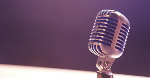 A vintage silver microphone with blue accents against a soft purple background, illustrating VoIP security concerns