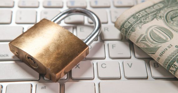 A padlock and dollar bills on a computer keyboard, illustrating cloud security for small businesses