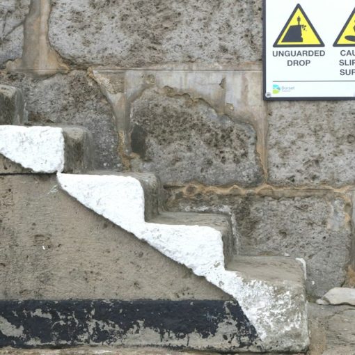 A sign on a stone wall warning of danger, illustrating seven deadly sins of cloud computing