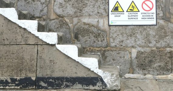 A sign on a stone wall warning of danger, illustrating seven deadly sins of cloud computing
