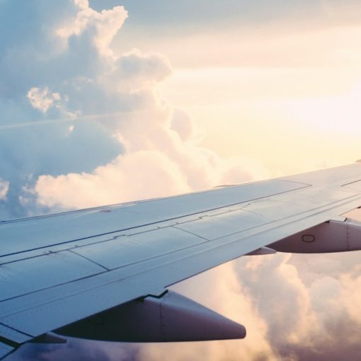 Airplane wing above the clouds at sunrise, illustrating reasons to move your business to the cloud