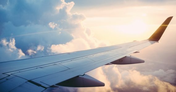Airplane wing above the clouds at sunrise, illustrating reasons to move your business to the cloud