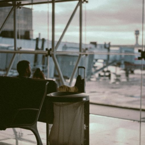 Man sitting in an airport boarding area, illustrating less dependence on a single device