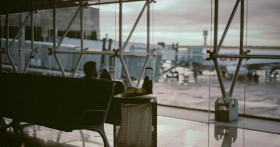 Man sitting in an airport boarding area, illustrating less dependence on a single device