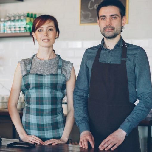 Two cafe workers standing behind a counter, illustrating small businesses working in the cloud