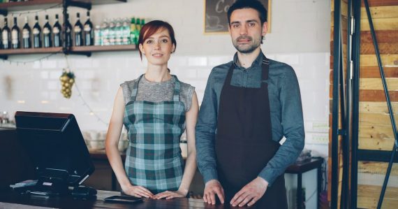 Two cafe workers standing behind a counter, illustrating small businesses working in the cloud