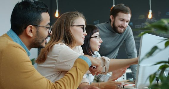 Diverse team collaborating around a computer screen, illustrating the cloud as the way forward for SMBs