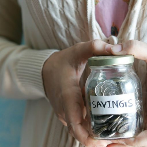 A woman holding a jar with savings written on it, illustrating small companies seeking cloud savings