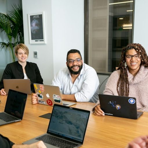 Four people on laptops listening to a speaker in a board meeting, illustrating VoIP and small business collaboration