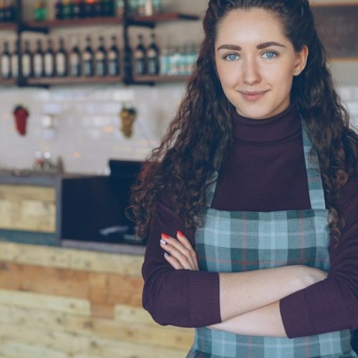 A smiling woman stands in her coffee shop, illustrating cloud computing and small business success