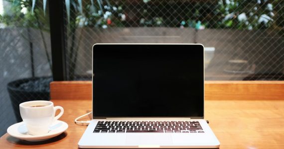 Laptop computer beside coffee mug, illustrating cloud computing for small startups
