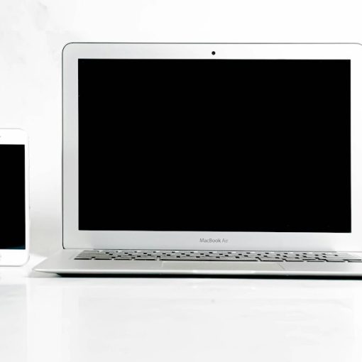 A white laptop computer sitting next to a cell phone, illustrating smartphones as laptop surrogates