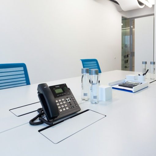 Black ip desk phone on white table, illustrating SMBs adopting VoIP and IP PBX