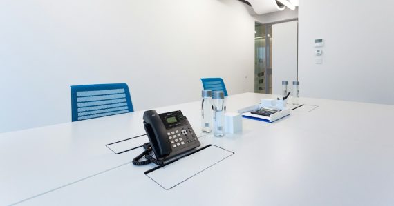Black ip desk phone on white table, illustrating SMBs adopting VoIP and IP PBX