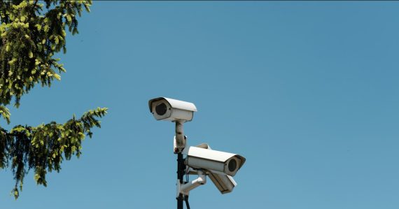 Two white security cameras mounted on a pole, illustrating US spy agencies adopting cloud computing
