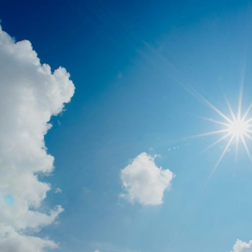 Sun shining in a blue sky with white clouds, illustrating a sunny forecast for cloud computing