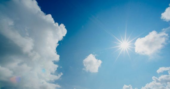 Sun shining in a blue sky with white clouds, illustrating a sunny forecast for cloud computing