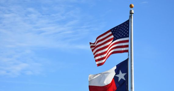 Two american and texas flags waving in the wind, illustrating VCE headquarters in Texas