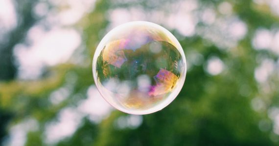 A close up of a soap bubble with trees in the background, illustrating unified communications spending