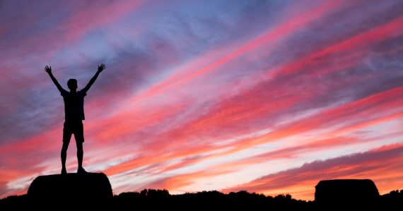 Silhouette of man standing on high ground under red and blue skies, illustrating making virtual desktop projects succeed
