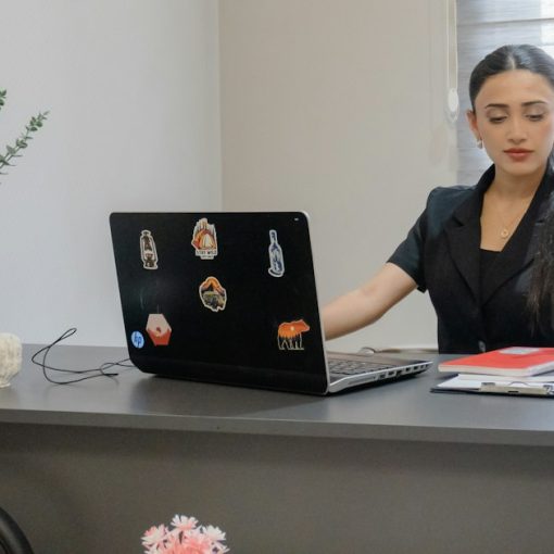 Woman working at desk with laptop and phone, illustrating virtual PBX adoption